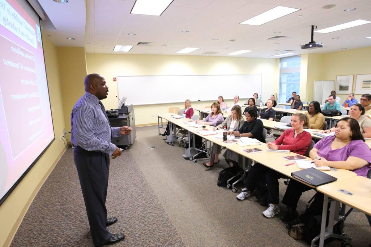 Teacher instructing older students at the front of a classroom